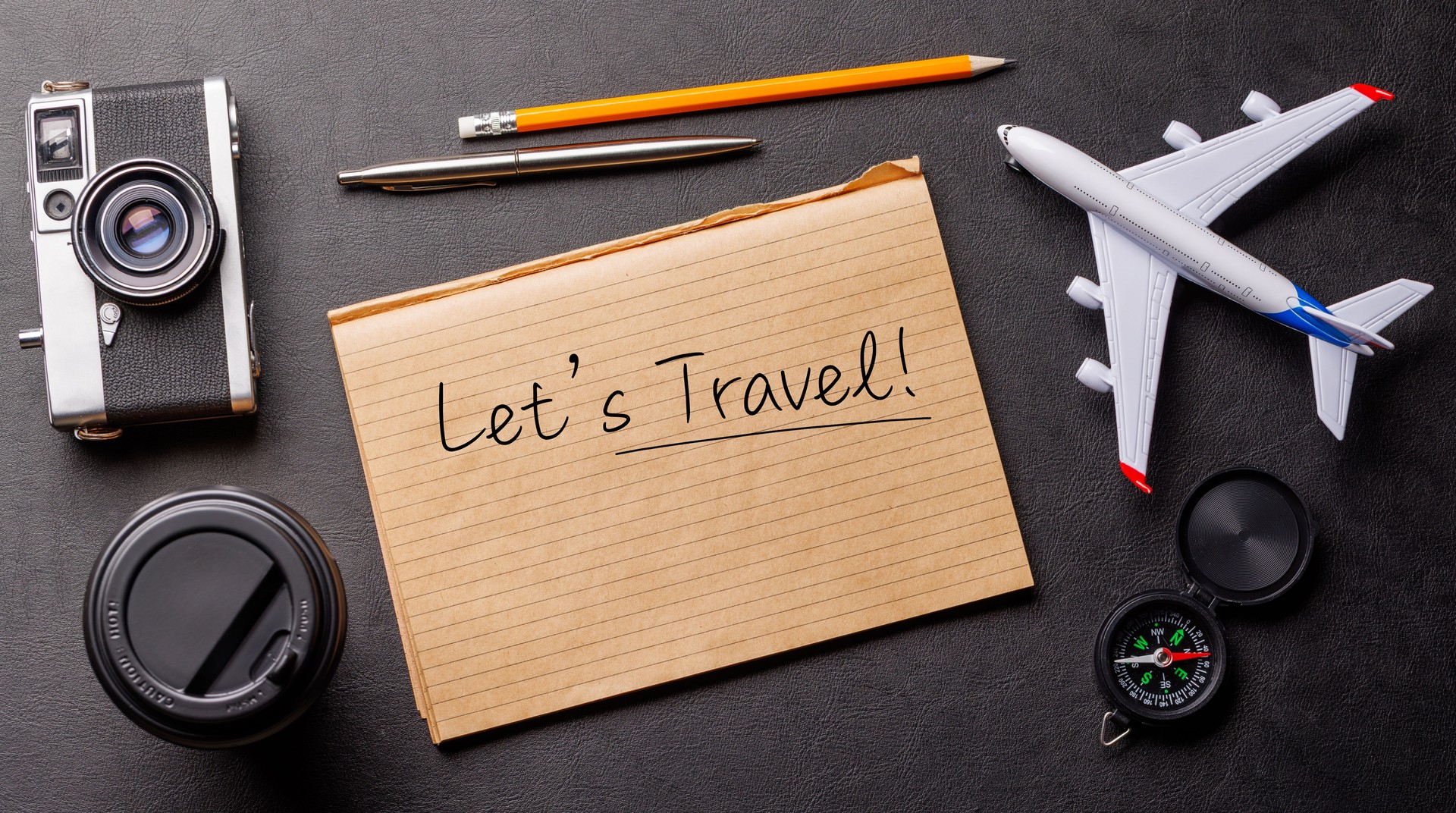 Creative flat lay of a travel-themed desk with notepad for plans